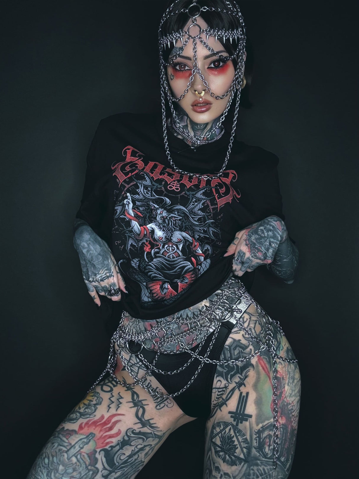 Ein schwarzes Grafik-T-Shirt mit einem rot-weißen dämonischen Design, das das Wort ‚something‘ in stilisierten Buchstaben über einer aufwendigen Illustration zeigt.