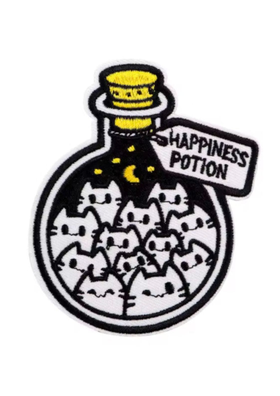 Ein gestickter Aufnäher mit einer Flasche voller Cartoon-Katzen und dem Etikett ’Happiness Potion’.