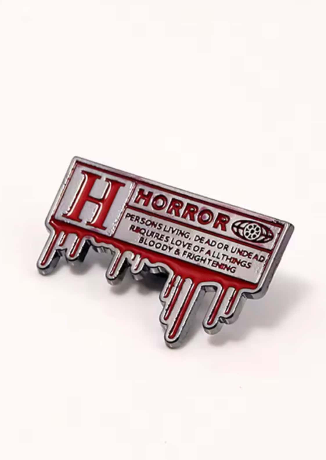Roter und silberner emaillepin in tropfenform mit dem wort horror in fetten buchstaben für gothische looks