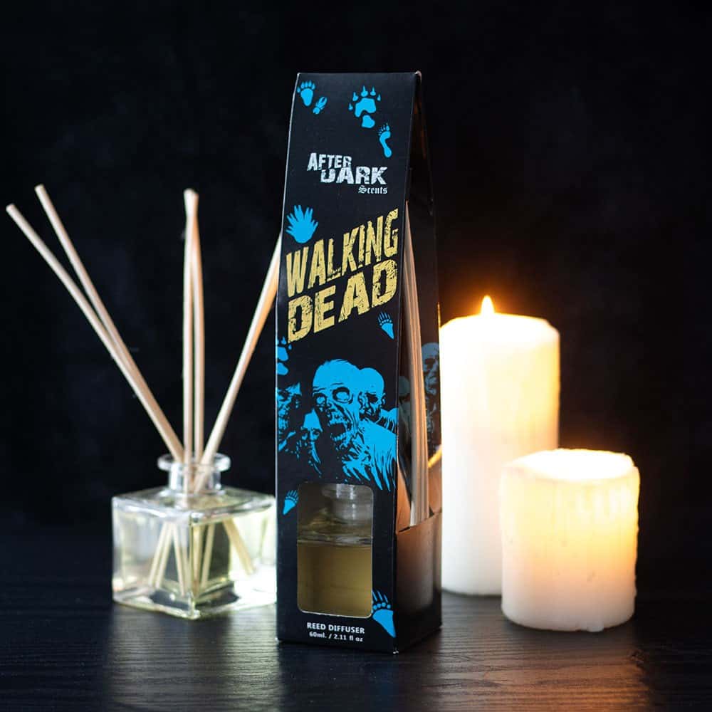 Schwarze rechteckige box mit blauer und goldener walking dead marke, zombie-illustration und durchsichtigem fenster mit bernsteinfarbenem walking dead reed diffuser flüssigkeit