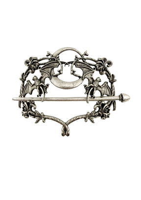 Silberfarbene Metallbrosche mit aufwendigen Fledermaus- und Blumenmustern um einen zentralen Halbmond.