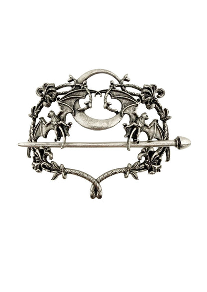 Silberfarbene Metallbrosche mit aufwendigen Fledermaus- und Blumenmustern um einen zentralen Halbmond.