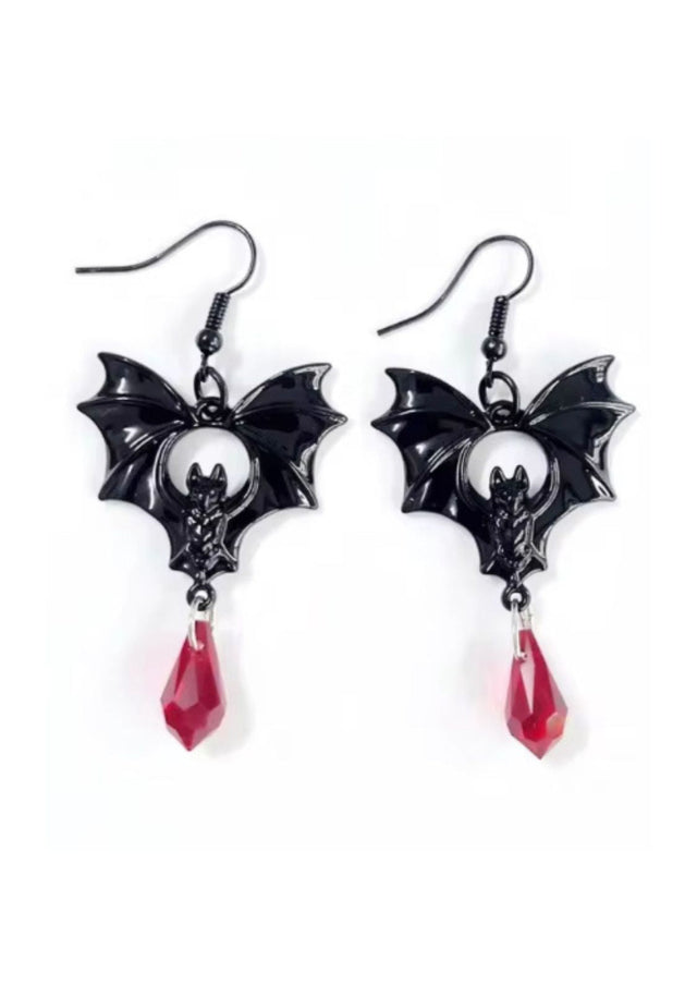 Fledermausförmige Ohrringe mit roten Kristalltropfen, schwarzen und silbernen Akzenten.