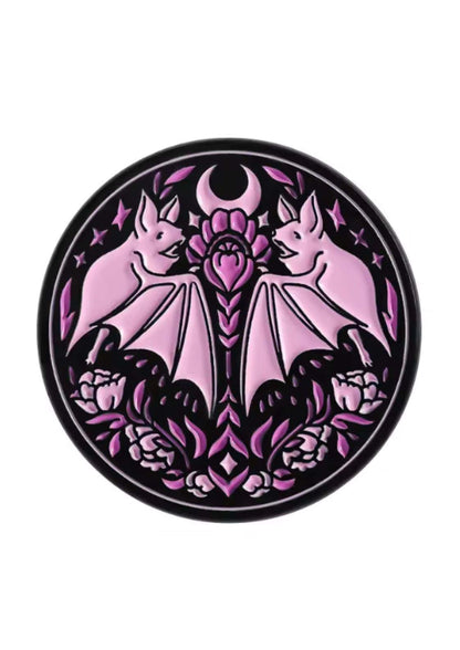 Rosa Emaille-Anstecknadel in Form einer Fledermaus mit violetter Lotusblume und Mondsichelmotiv.