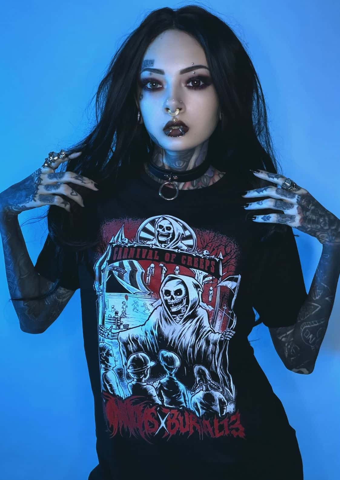 Schwarzes T-Shirt mit einem Grafikdruck eines Skeletts in einer Kapuzenrobe, das eine Flagge hält, mit roten und weißen Details und dem Text ‚carnival of ghouls‘ darüber.