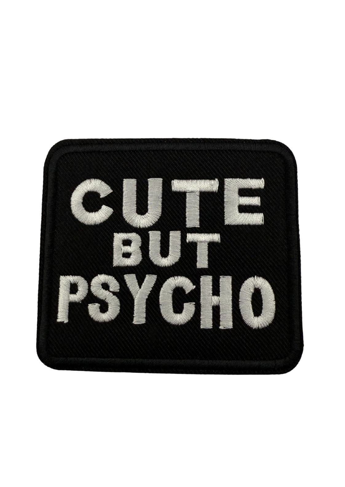 Schwarzer gestickter Aufnäher mit weißer Schrift ’CUTE BUT PSYCHO’.