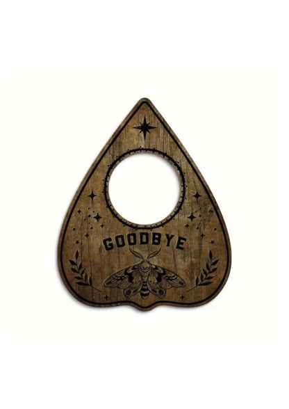 Eine rustikale, holzene, tränenförmige Ouija-Planchette mit einem zentralen Loch, graviertem schwarzem Text, der ‚goodbye‘ lautet, und detaillierten Illustrationen von Sternen, Lorbeerblättern und einem Insekt.