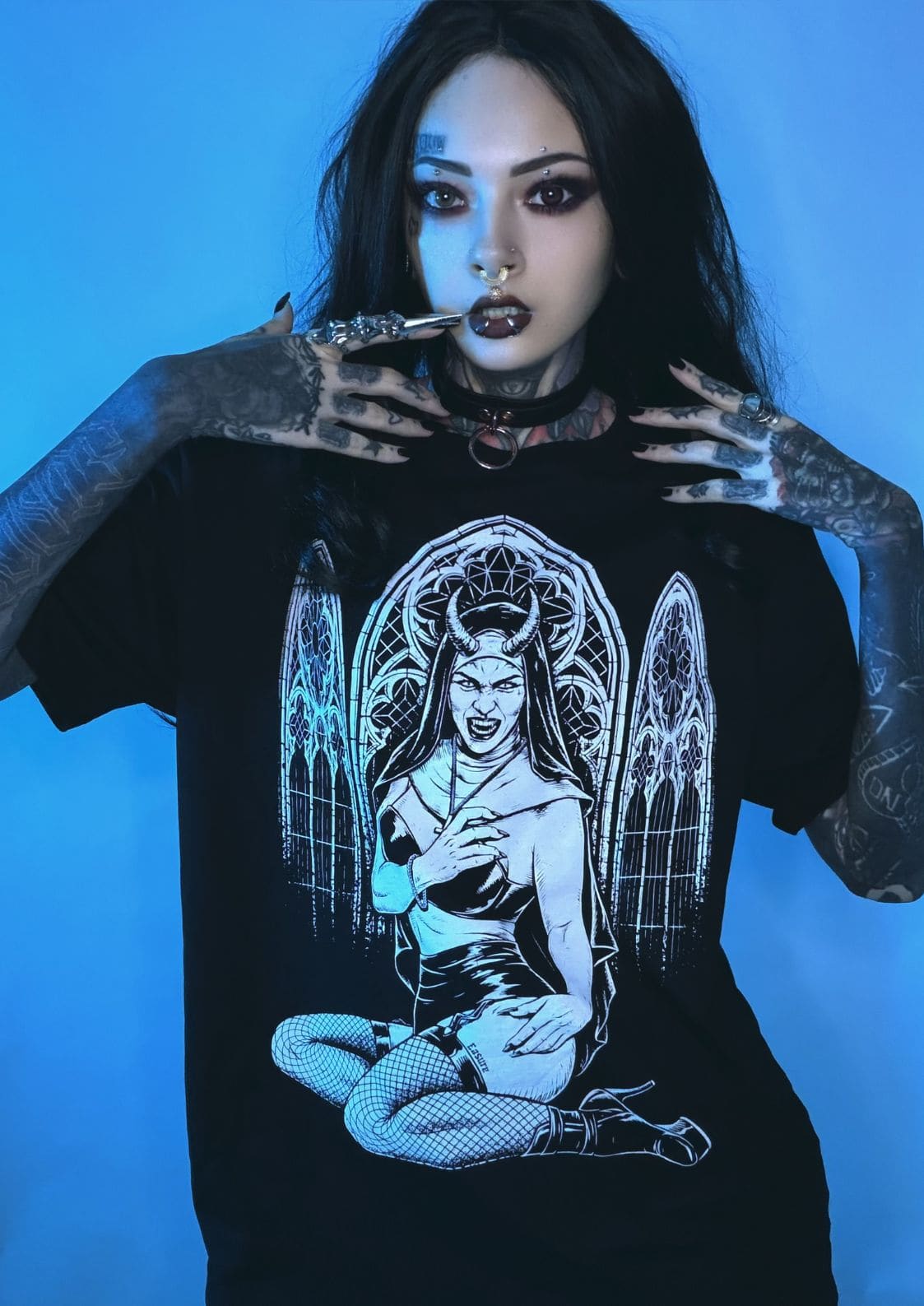 Schwarzes T-Shirt mit weißem Grafikmotiv eines engelhaften Dämons mit Flügeln und Hörnern, sitzend in einem gotischen Bogen-Design