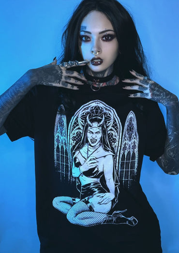 Schwarzes T-Shirt mit weißem Grafikmotiv eines engelhaften Dämons mit Flügeln und Hörnern, sitzend in einem gotischen Bogen-Design