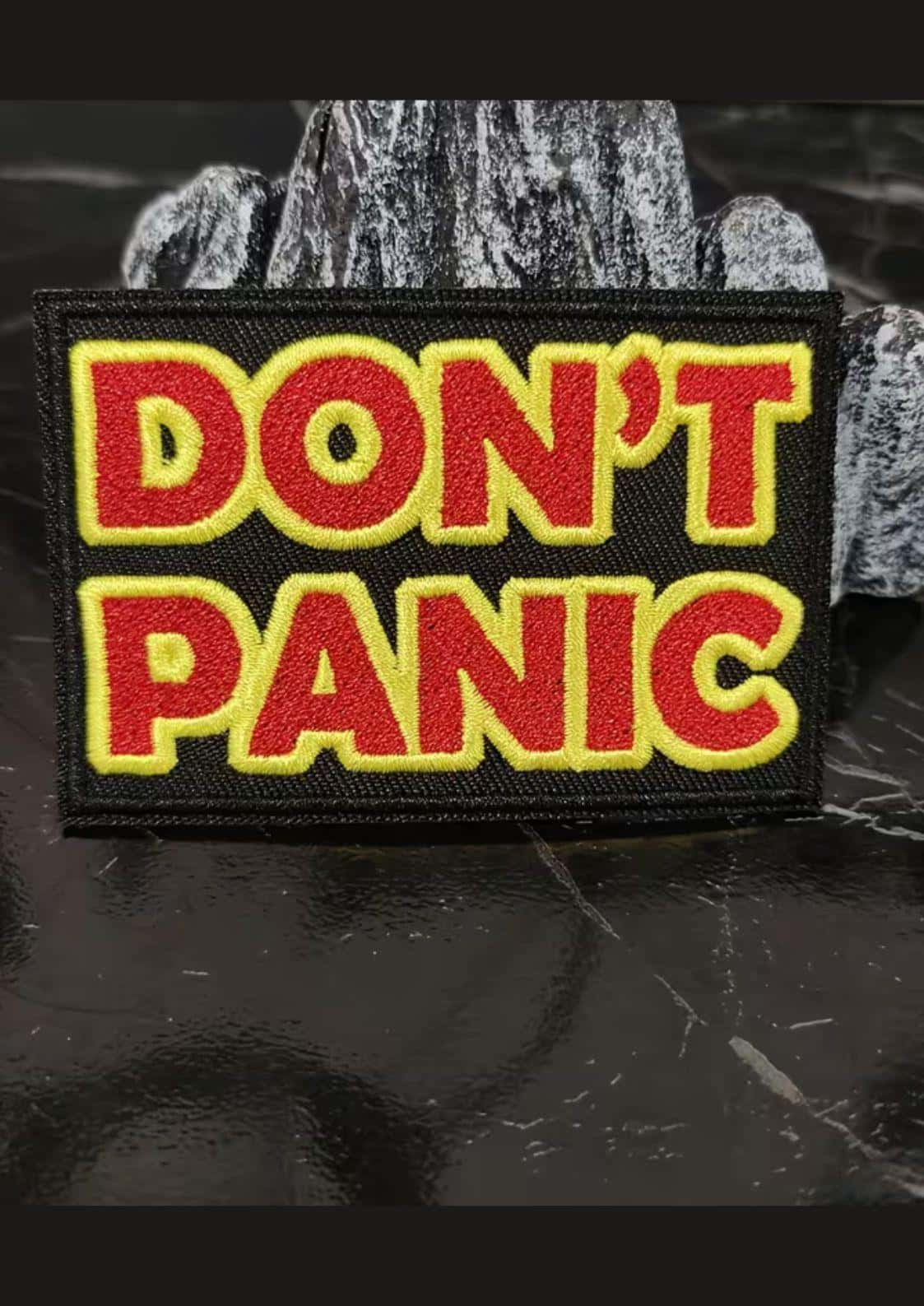 Schwarzer bestickter patch mit kräftigem rotem und gelbem don´t panic text für gothic und dark fashion fans
