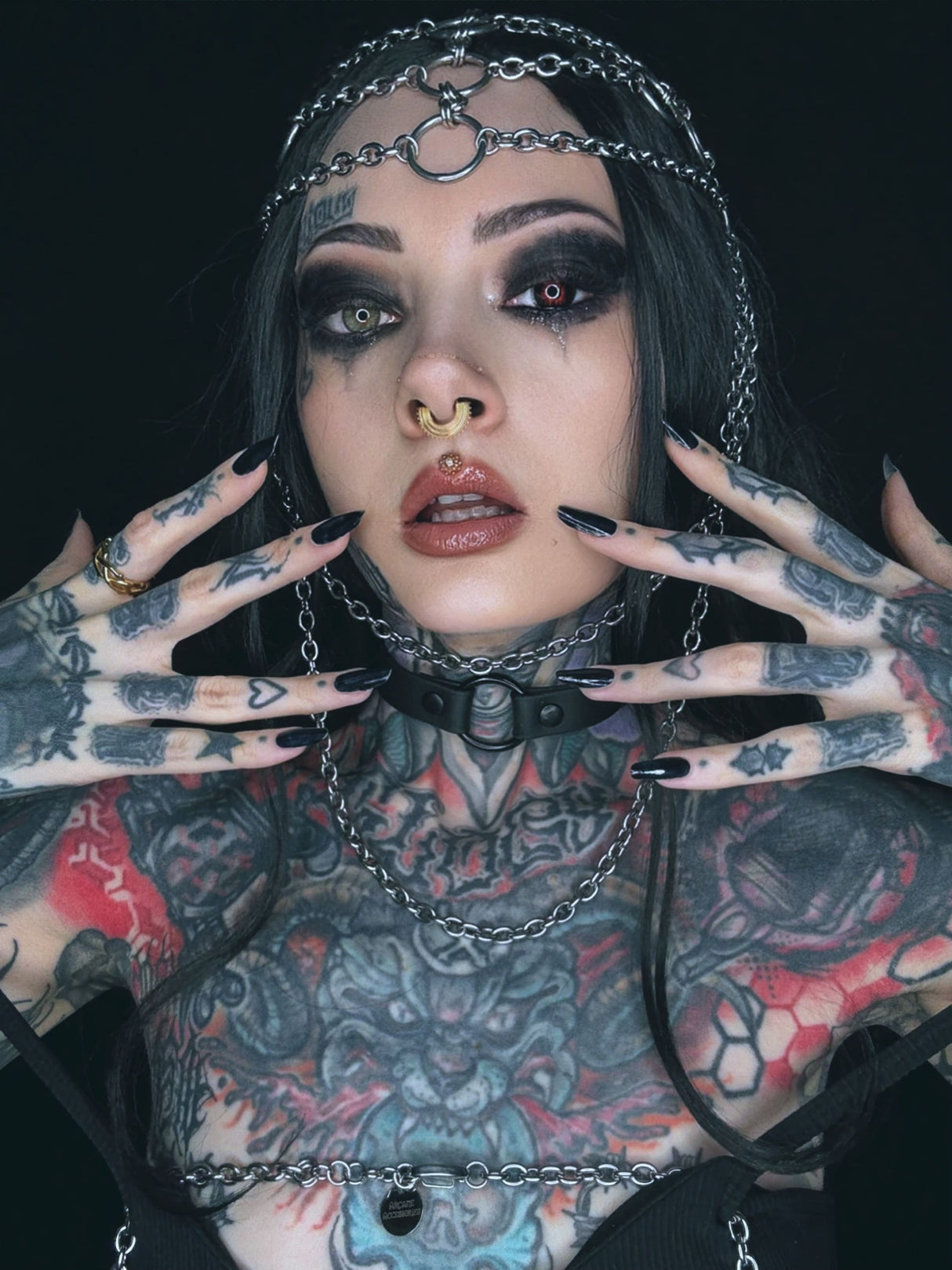 Tätowierte Frau mit Ketten und dunklem Make-up.