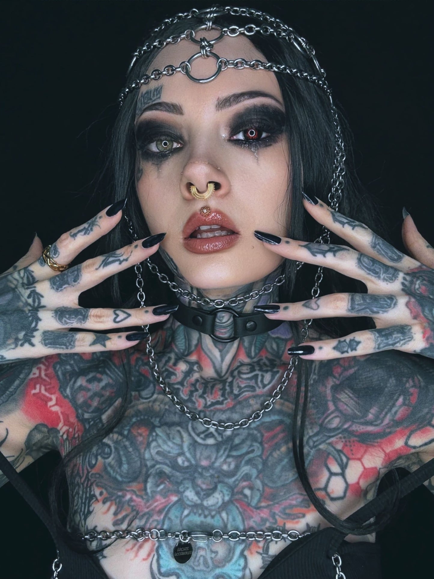 Tätowierte Frau mit Ketten und dunklem Make-up.