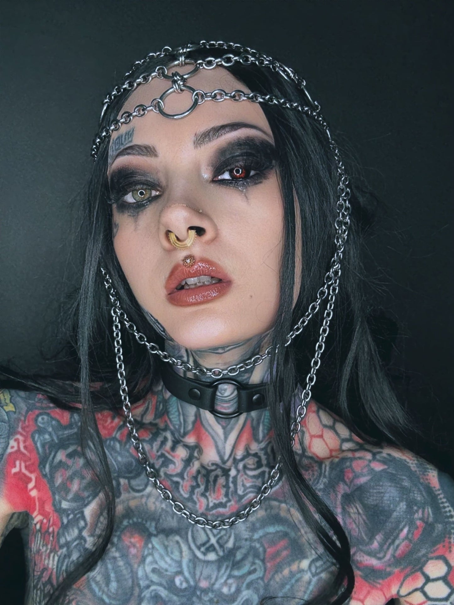 Tätowierte Frau mit Kettenkopfbedeckung und Halsband.