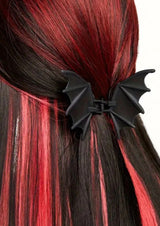 Schwarzer Fledermausflügel-Haarclip mit glänzender Oberfläche und spitzen Flügeln, wahrscheinlich aus Plastik oder Harz gefertigt.