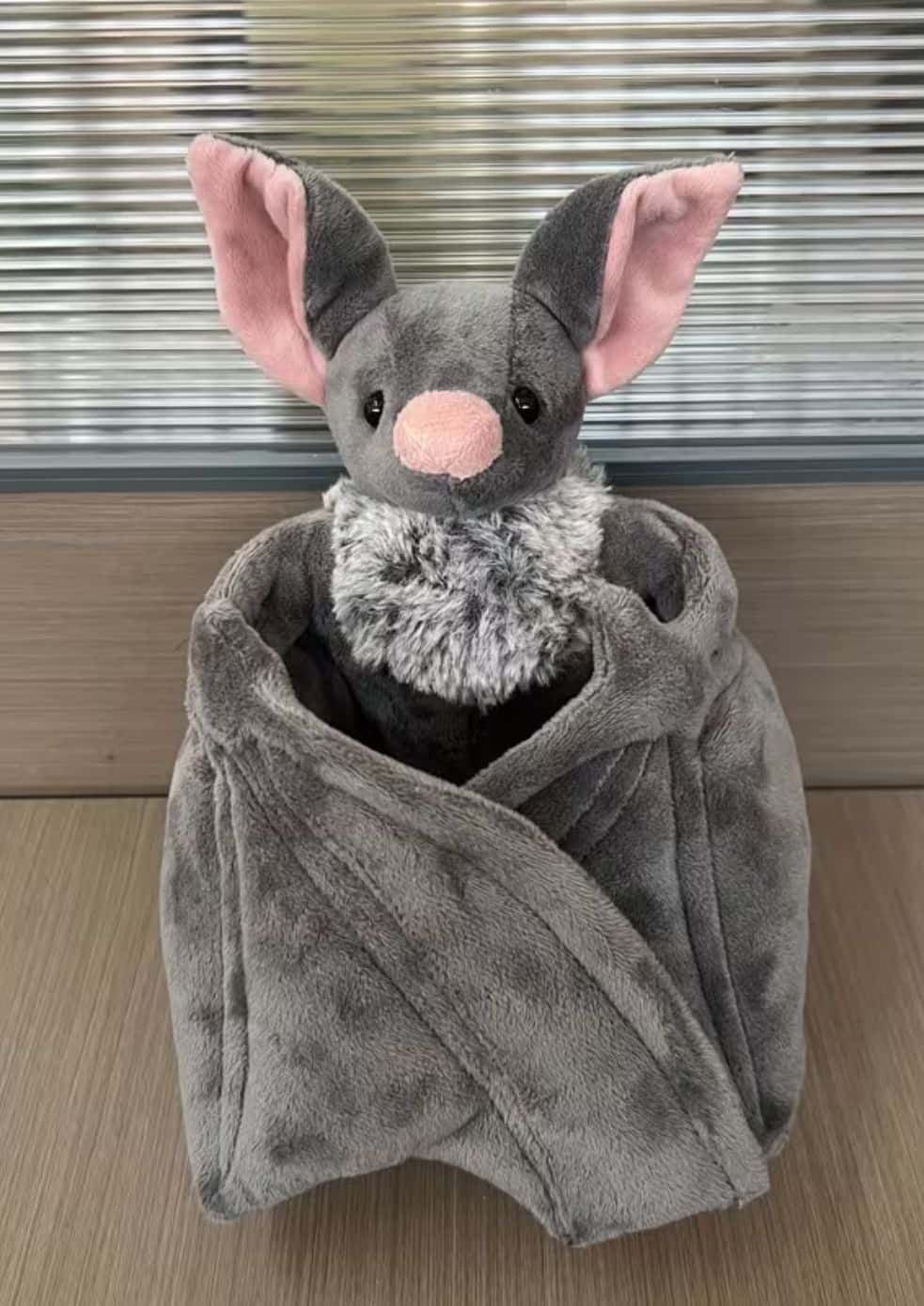 Graues fledermaus plüschtier mit rosa innenohren und nase, eingewickelt in eine passende fuzzy decke, gothic style