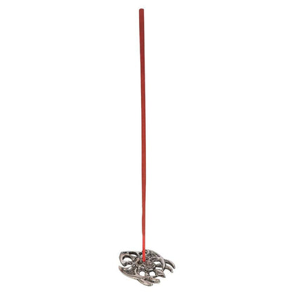 A slender red away evil incense stick stands upright in an ornate silver-toned metal holder with spider-like design
