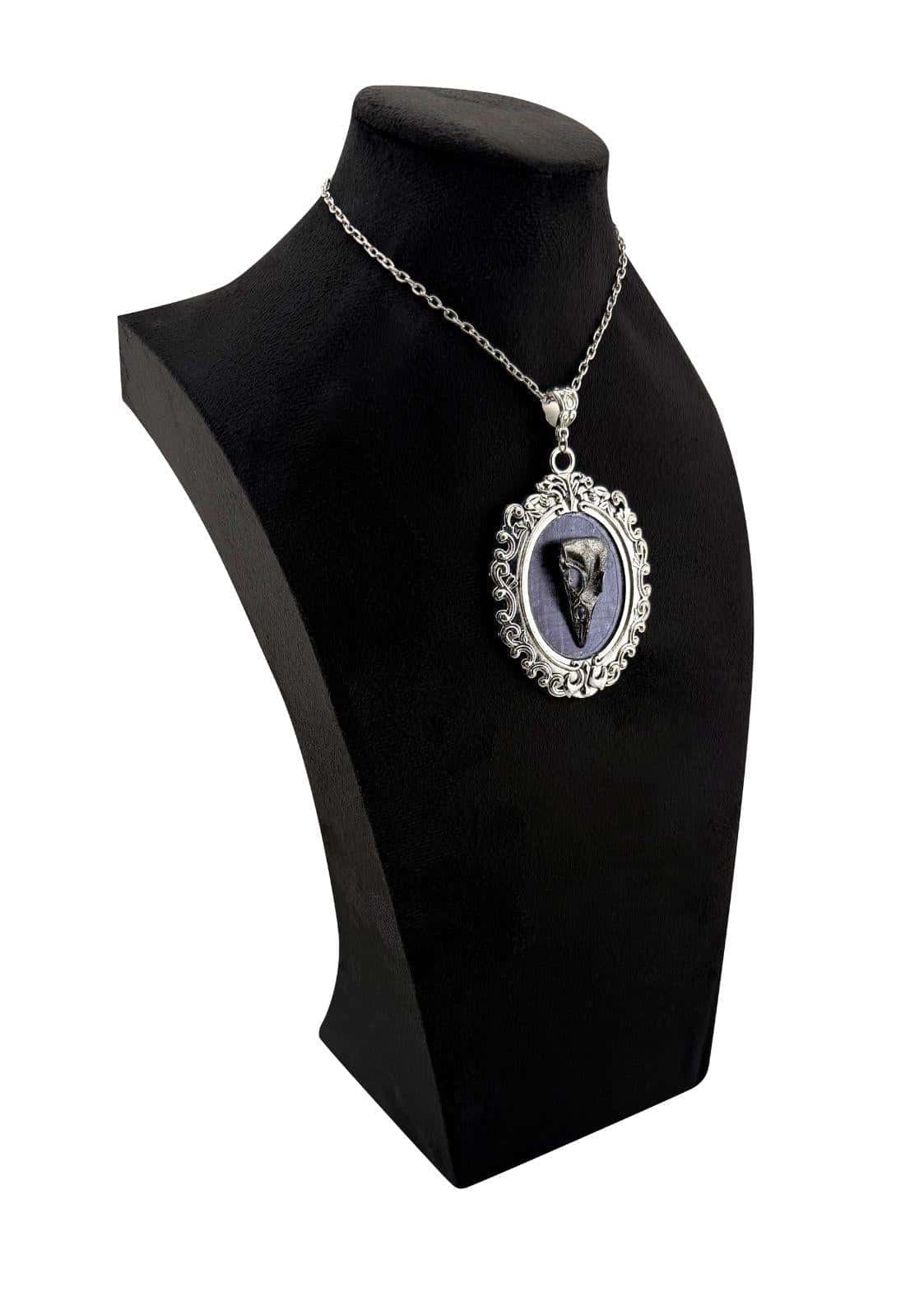 Silberne ornate halskette mit gothic crow skull anhänger und dunkel fossilisiertem zahn im ovalen rahmen