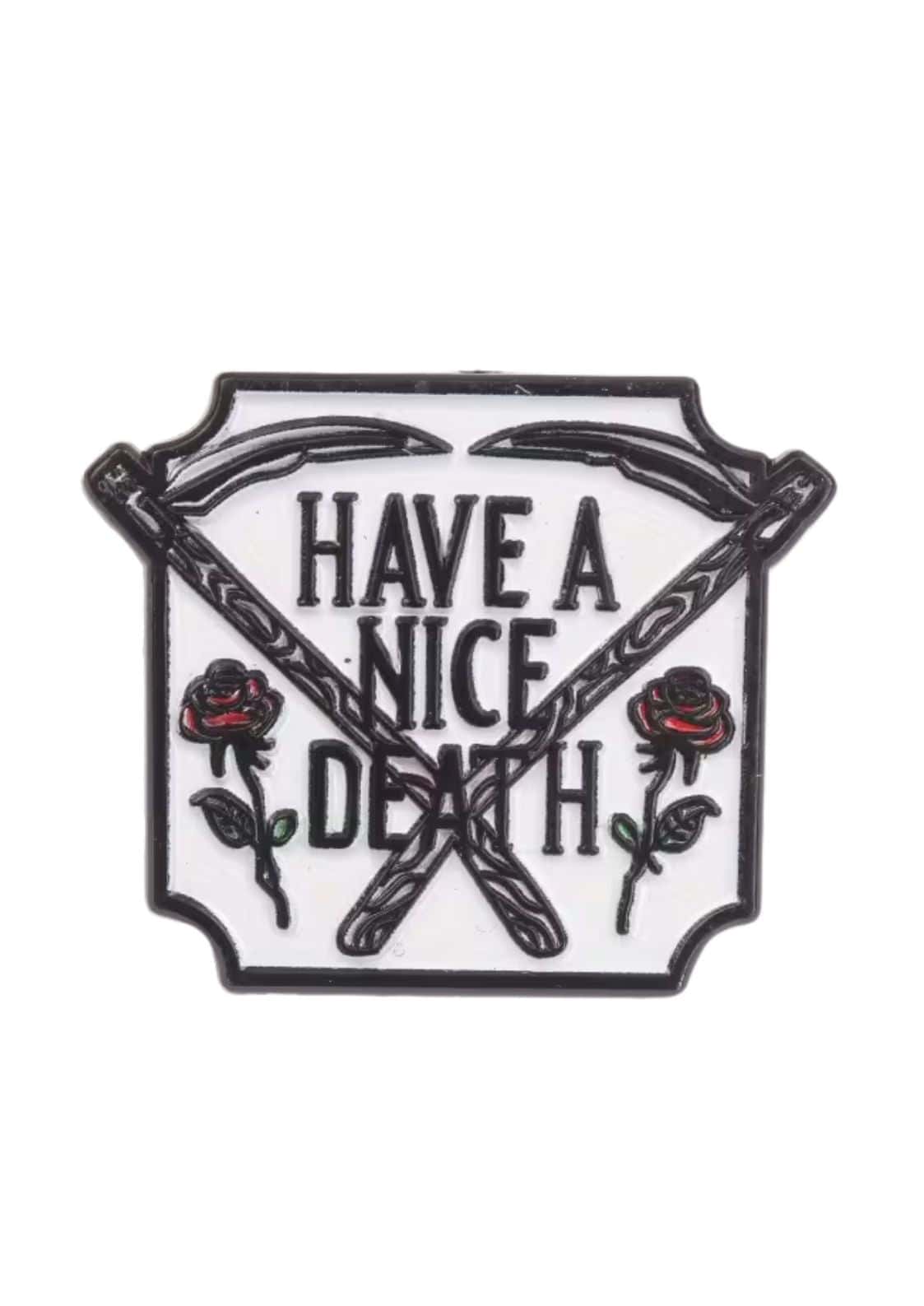 Weißer Emaille-Anstecker mit schwarzem Rand, gekreuzten Sensen und roten Rosen neben ’Have a nice death’ in fetter schwarzer Schrift