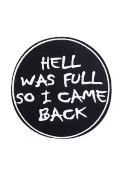 Schwarzer runder Aufnäher mit weißem Text „die Hölle war voll, also bin ich zurückgekommen“assistant: schwarzer runder Aufnäher mit dem Spruch „die Hölle war voll, also bin ich zurückgekommen“ in fetter, weißer Schrift.