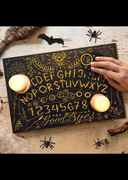 Schwarzes horned skull small ouija board mit goldenen buchstaben und symbolen zwei kerzen im klassischen ouija-tradition style