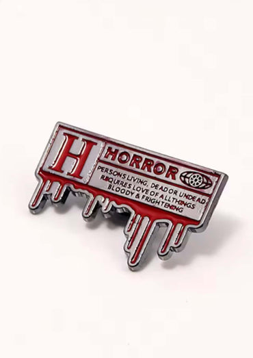 Roter und silberner emaillepin in tropfenform mit dem wort horror in fetten buchstaben für gothische looks
