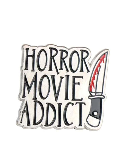 Silberner enamel pin mit der aufschrift horror movie addict in schwarzer schrift und einem blutroten messer, gothik fashion