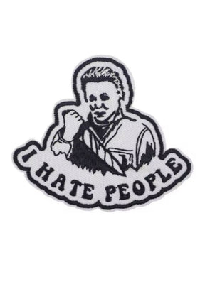 Weißer und schwarzer gestickter Aufnäher mit einer Person, die ein Messer hält, und dem Text ’I HATE PEOPLE’.
