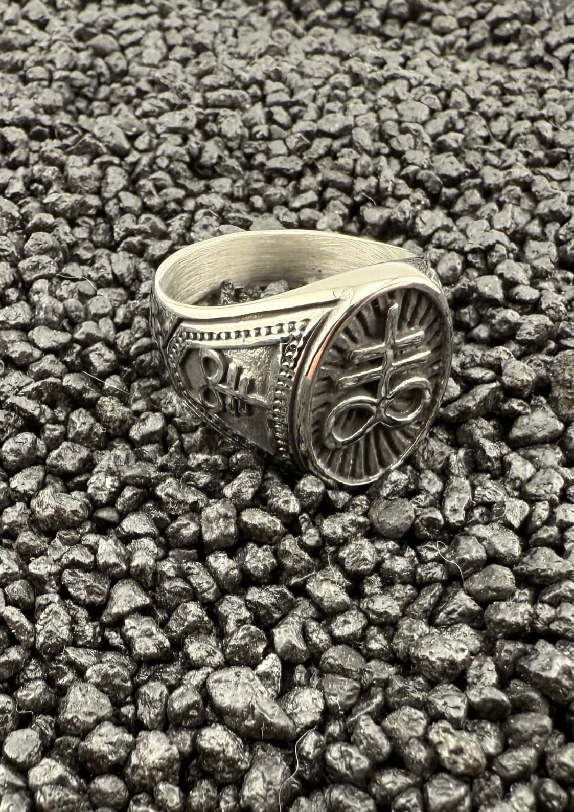 Silberner, verzierten Ring mit Blumenmuster auf schwarzem Lavafelsen-Hintergrund.