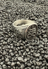 Silberner, verzierten Ring mit Blumenmuster auf schwarzem Lavafelsen-Hintergrund.