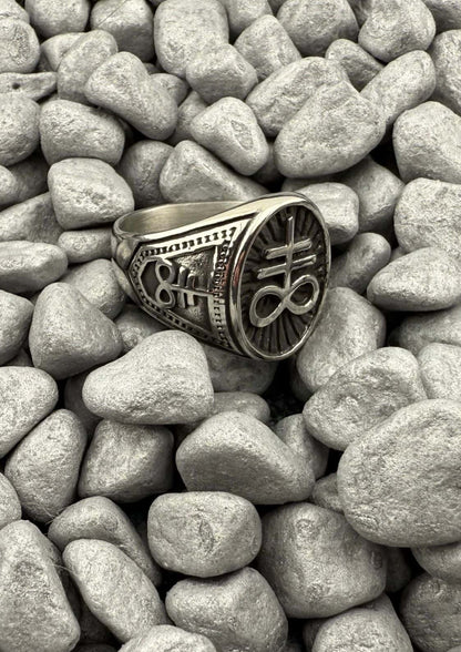 Leviathan ring aus edelstahl in silber mit eingraviertem sigil auf strukturiertem band auf grauen kieseln aus china