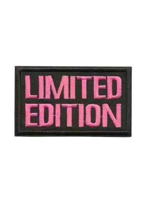 Limitierte Edition-Aufnäher mit geprägtem pinkem Text auf schwarzem Hintergrund.