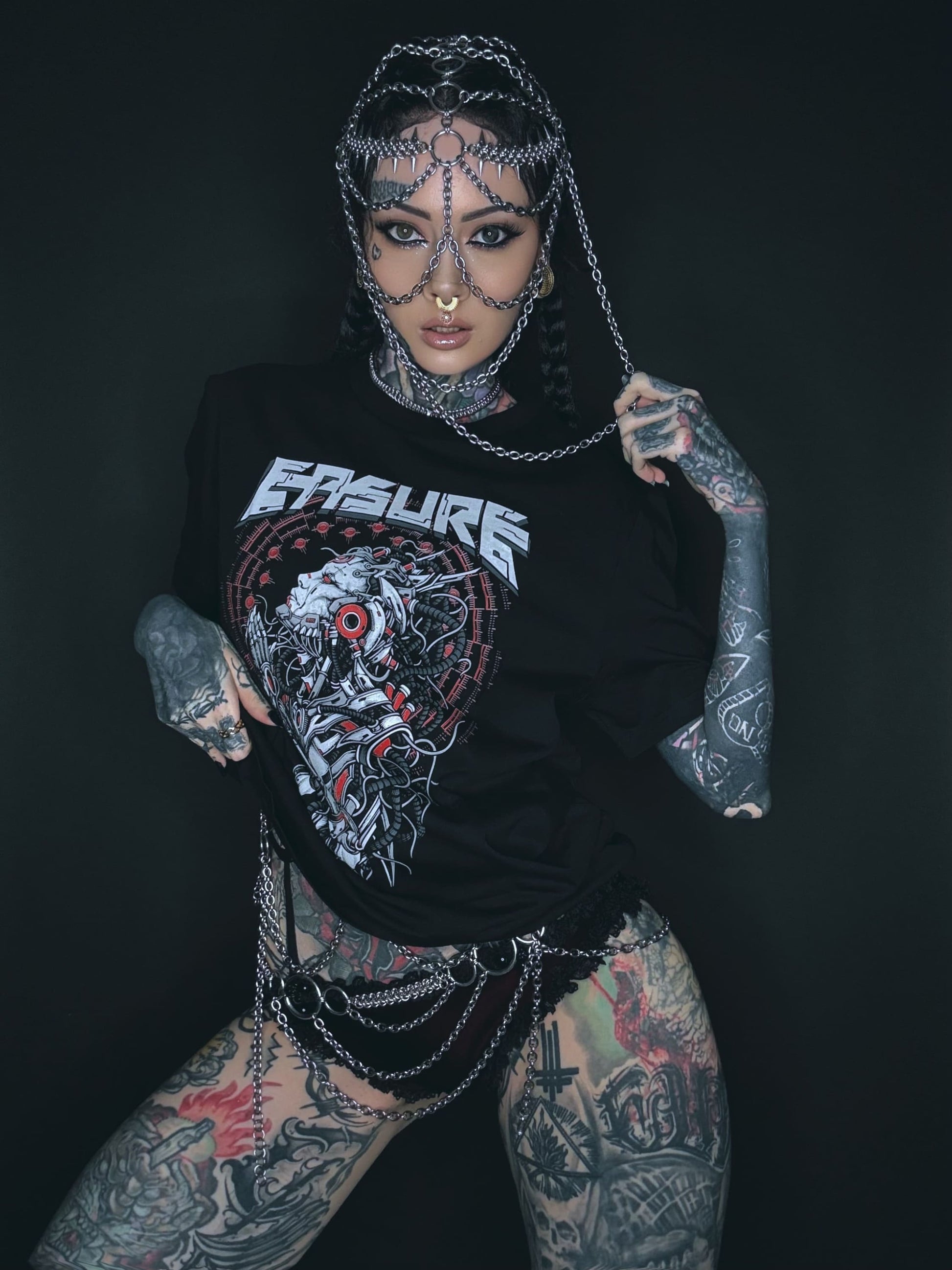 Tätowierte Frau mit Kettenkopfbedeckung und T-Shirt.