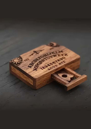Ein rustikales hölzernes Ouija-Brett mit eingravierten Buchstaben, Zahlen und Symbolen auf seiner Oberfläche.