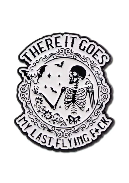 Weiß-schwarze Emaille-Anstecknadel mit einem Skelett und Fledermäusen.