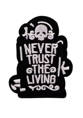 Schwarzer gestickter Aufnäher mit einem Totenkopf und der Aufschrift ’I NEVER TRUST THE LIVING’.