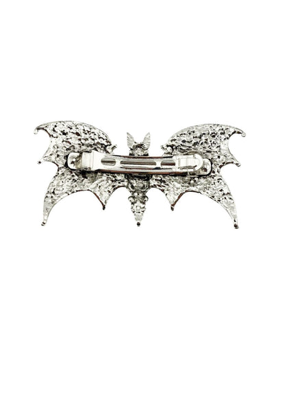 Silberne, fledermausförmige Brosche mit aufwendigen Details und einem zentralen Nadelmechanismus.