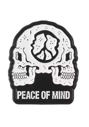 Black and white enamel pin featuring two skulls and a peace symbol labeled peace of mind for gothic horror fans
