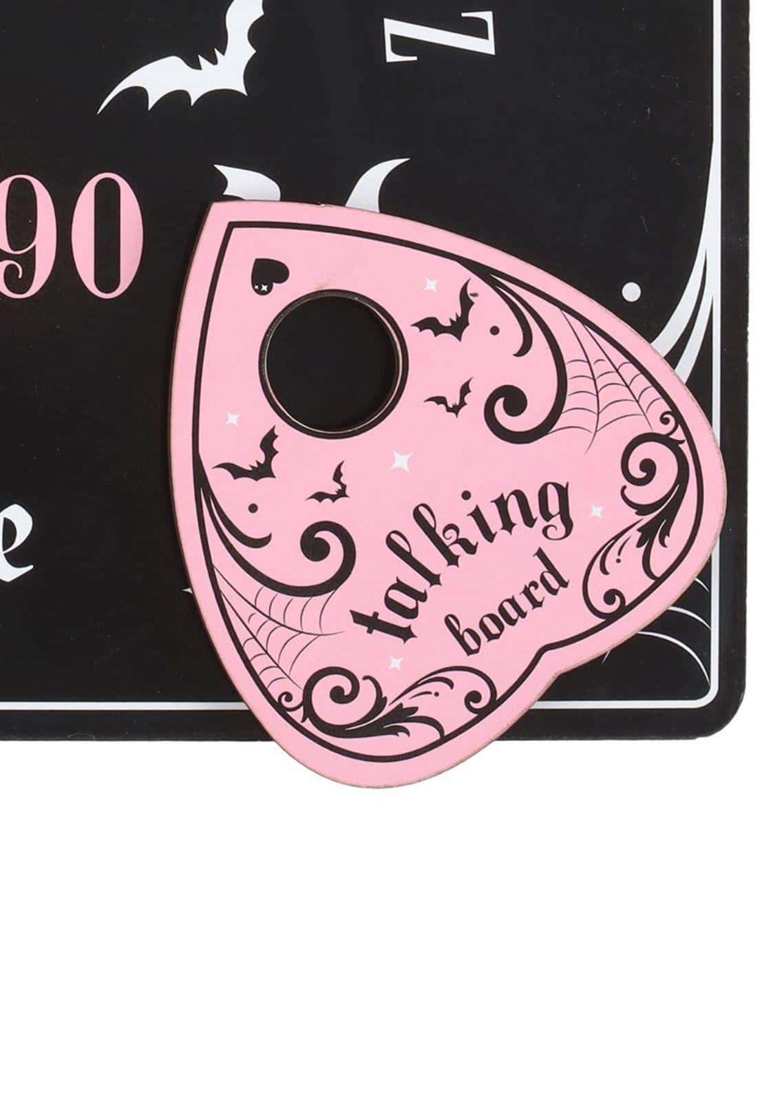 Pink and black ouija board with black ornate bat designs and a central hole on a pink talking board