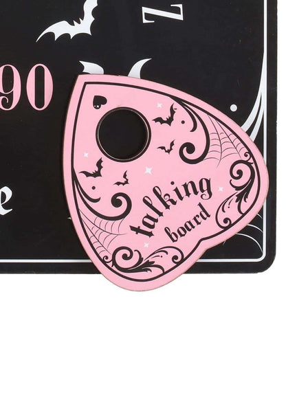 Pink and black ouija board with black ornate bat designs and a central hole on a pink talking board
