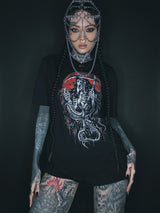 Tätowierte Frau, die einen Kettenkopfschmuck und ein grafisches T-Shirt trägt.