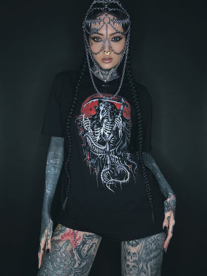 Tätowierte Frau, die einen Kettenkopfschmuck und ein grafisches T-Shirt trägt.