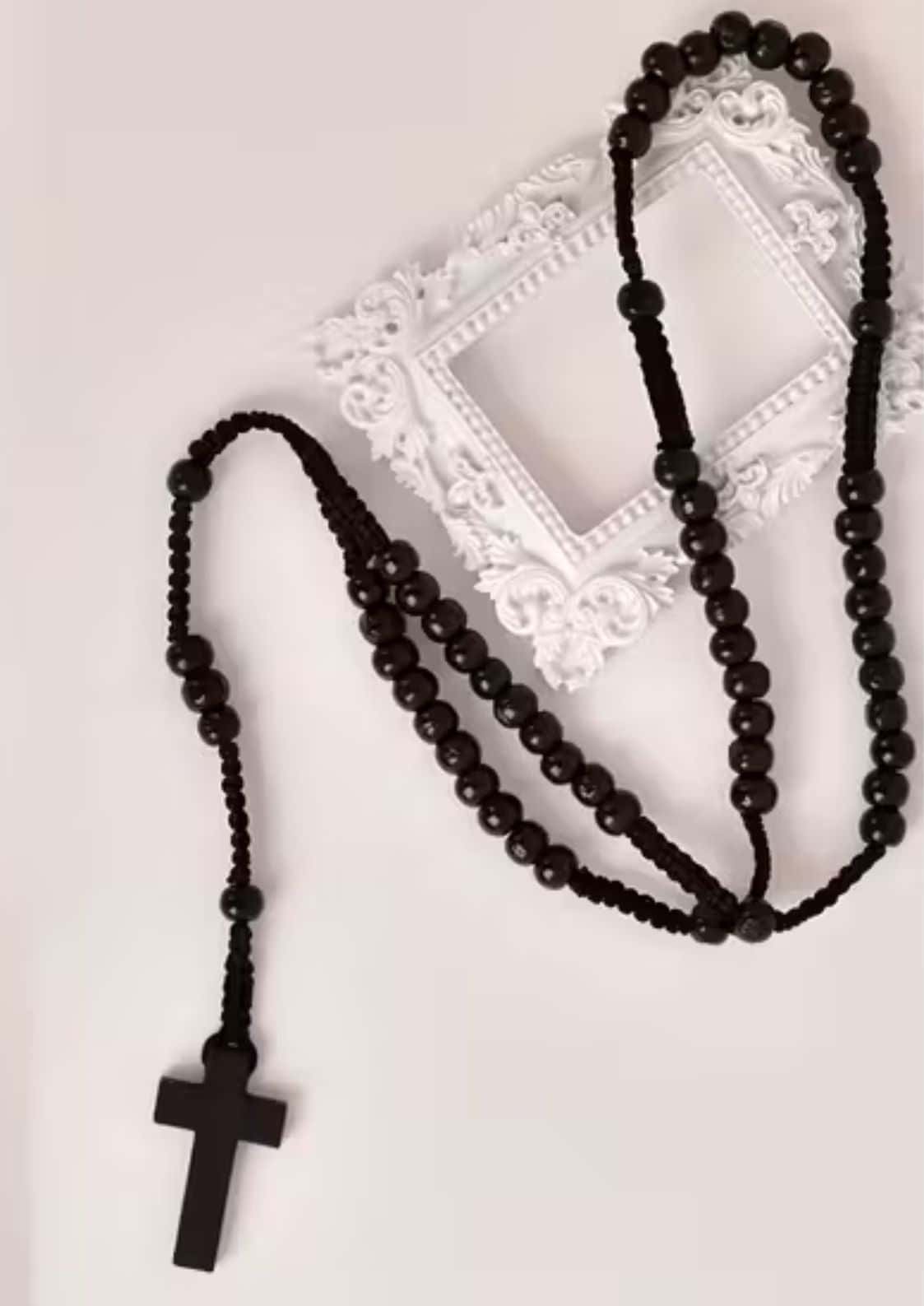 Schwarzes Perlenrosenkranz mit Holzkreuz-Anhänger, wahrscheinlich aus dunklem Holz oder Harz gefertigt.