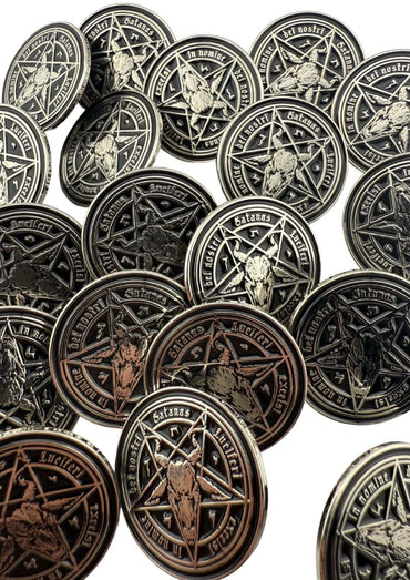 Ein Stapel silberfarbener, runder Metallmünzen, die ein Pentagramm und einen Ziegenkopf zeigen.