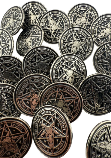 Ein Stapel silberfarbener, runder Metallmünzen, die ein Pentagramm und einen Ziegenkopf zeigen.