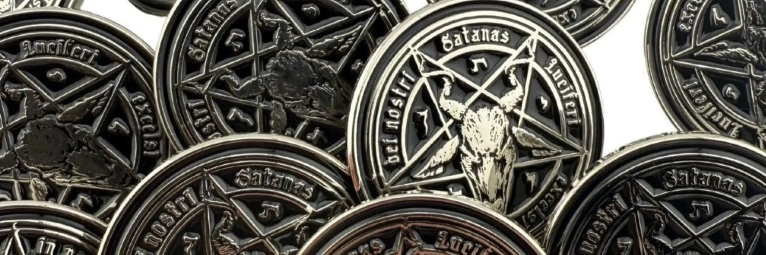 Schwarze metallische Münzen mit einem Pentagramm in der Mitte, das einen Ziegenschädel zeigt, und Inschriften wie 'satanas' und 'beelzebub.'