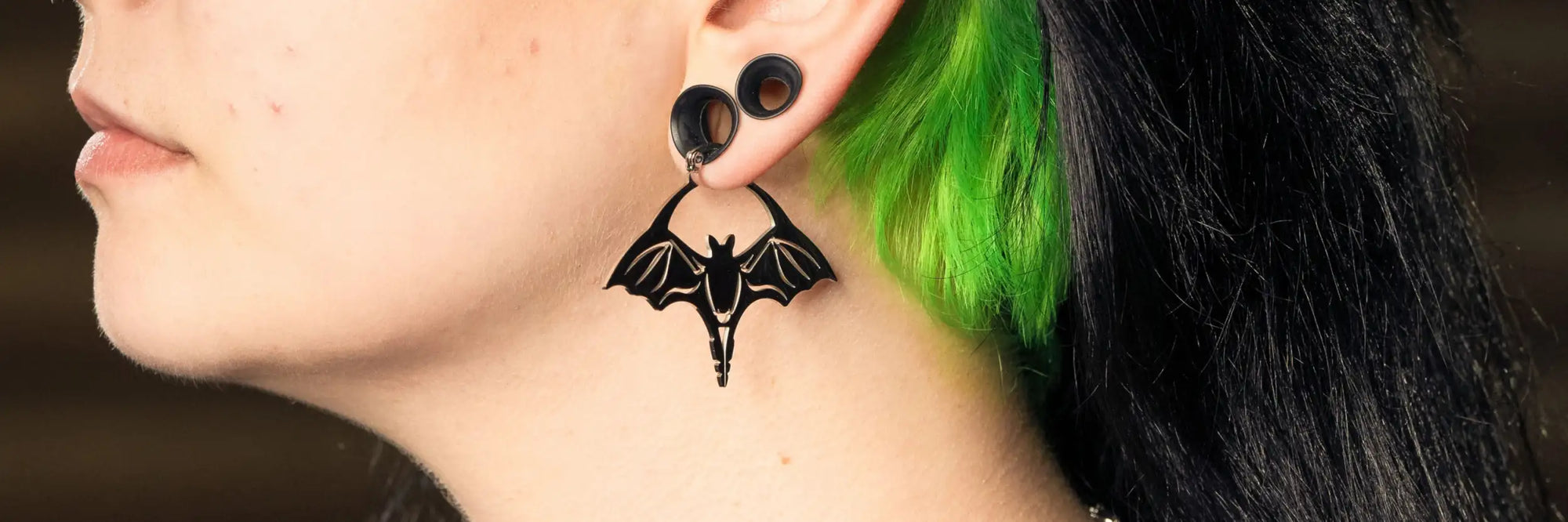 Schwarzer, fledermausförmiger Anhängerohrring mit einem schlanken, minimalistischen Design.