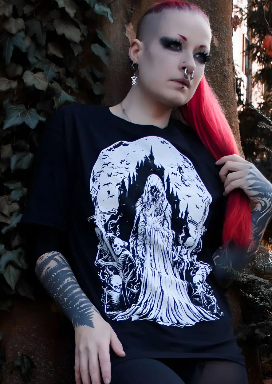 Schwarzes T-Shirt mit einem weißen Grafikmotiv einer geisterhaften Figur in einem fließenden Gewand, die vor einer Burg unter einem Vollmond steht, umgeben von Fledermäusen und Skeletten.