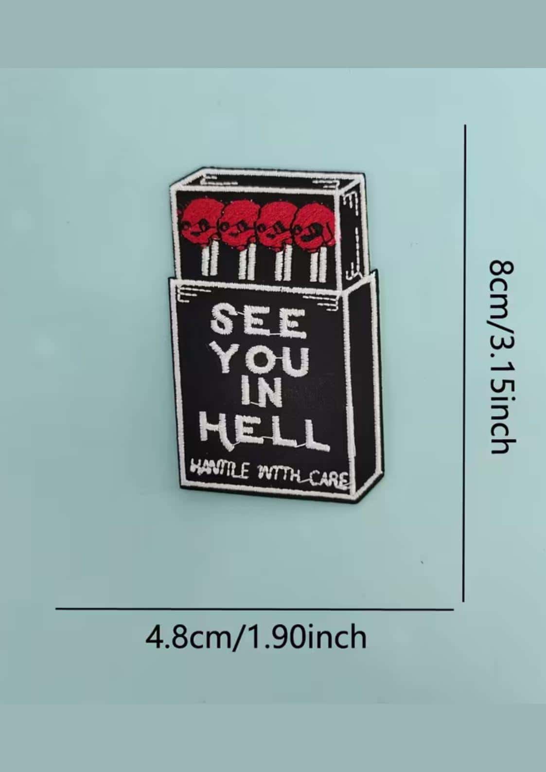 Schwarzer gothic enamel pin in form einer zündholzschachtel mit roten schädeln und weißem see you in hell schriftzug