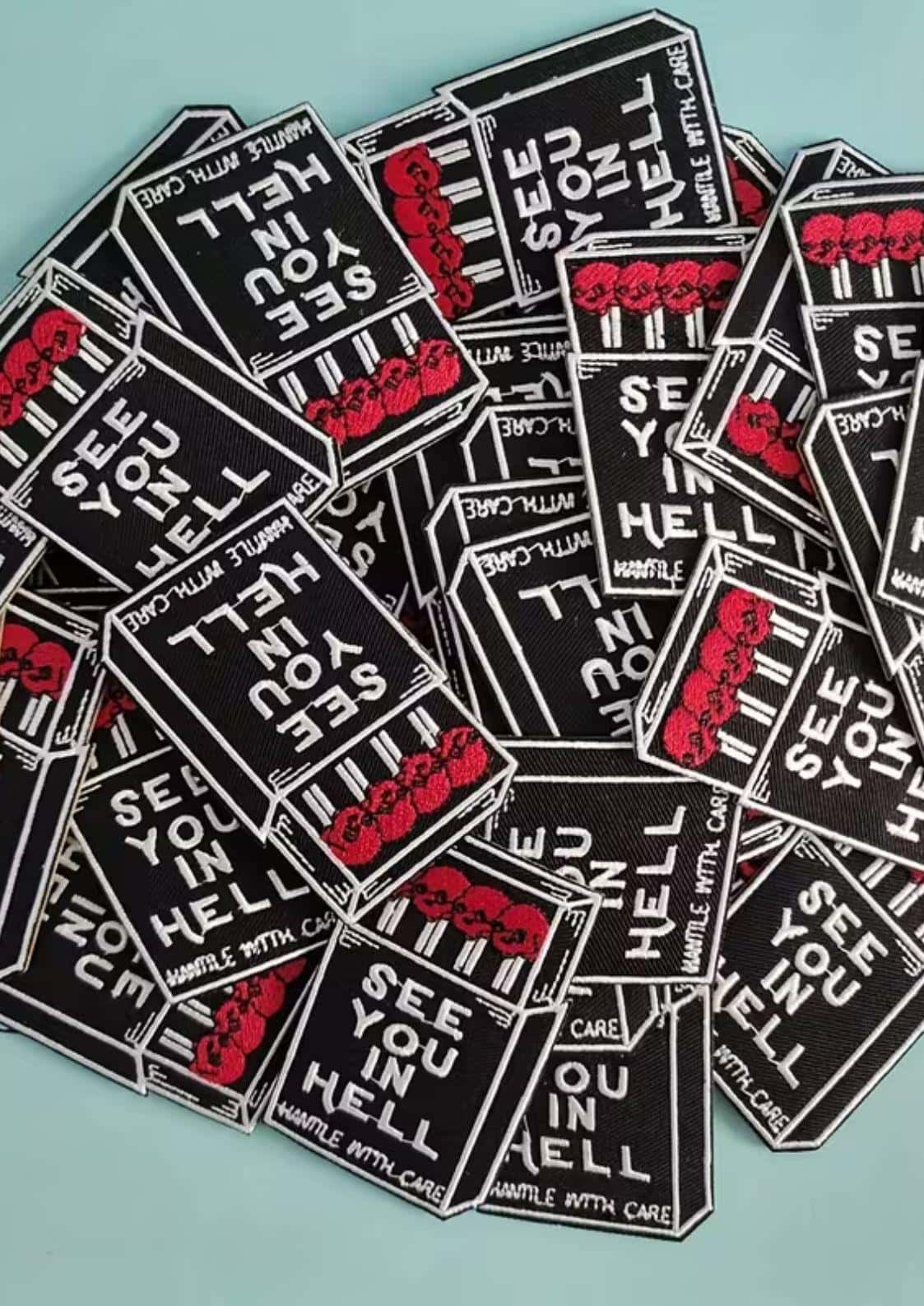 Schwarze und rote bestickte gothic patches in form von zündholzschachteln mit den texten see you in hell und handle with care für dark fashion