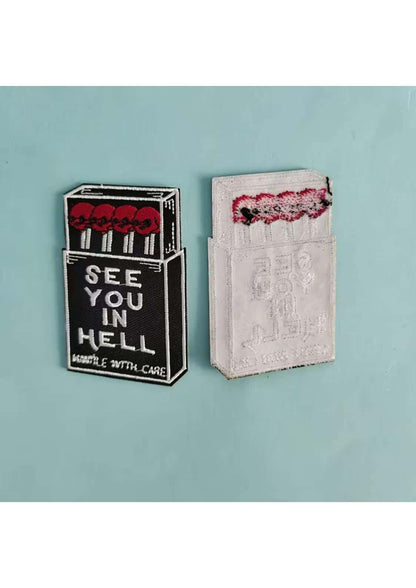 Schwarz-weiß bestickter patch im design eines zündholzschachts mit roten schädeln und dem text see you in hell für gothic kleidung und horror fans